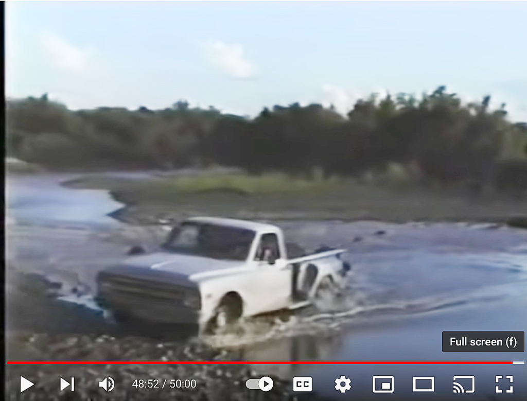 An old white pickup drives up on the muddy riverbank after crossing the Rio Grande
